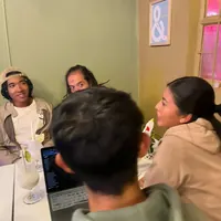 Tres personas conversando en una esquina del salón.