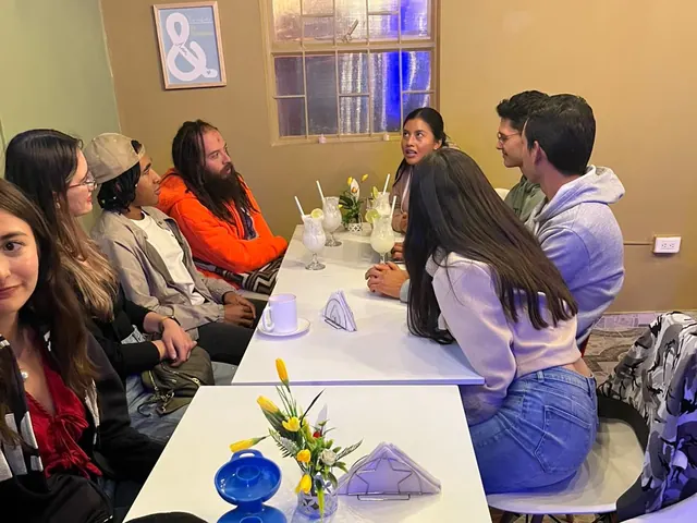 Las dos mesas del club llenas un viernes en la noche, con limonadas sobre la mesa y todos conversando.