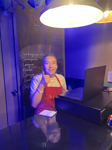Una asistente sonriendo con el computador abierto sobre la mesa.